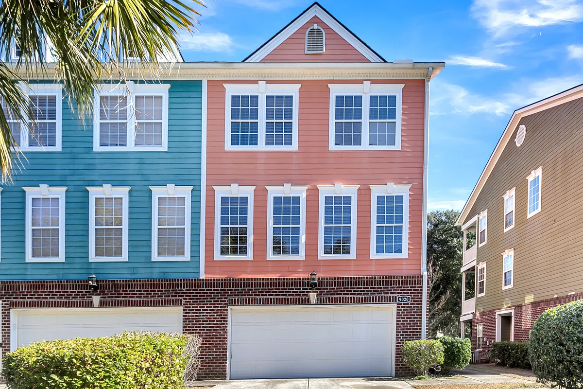A vibrant exterior view of the home, featuring a colorful façade, large windows, and landscaped bushes. The scene exudes a welcoming atmosphere, perfect for gatherings and outdoor relaxation.