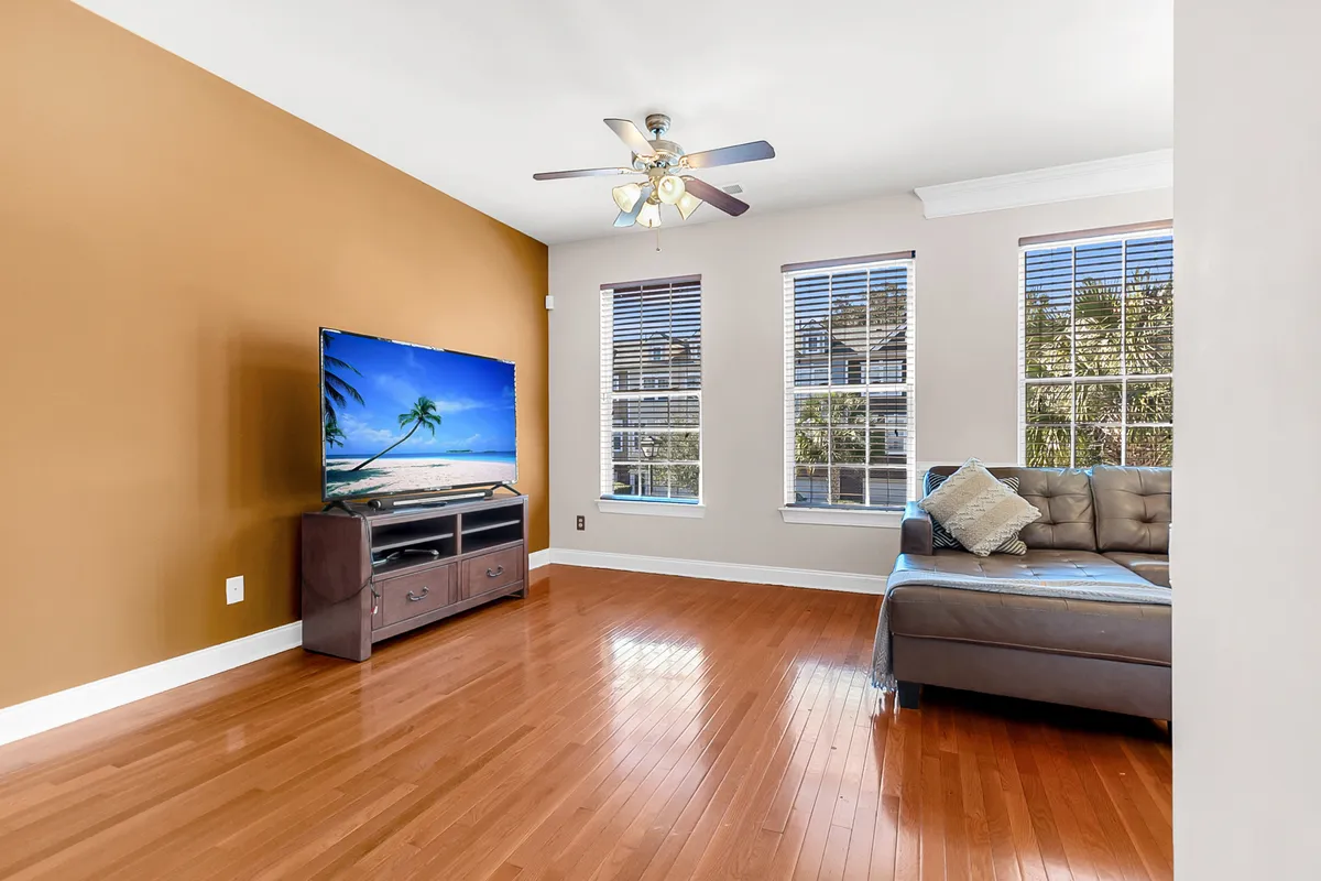 A comfortable living space with a large sectional sofa, a TV displaying a relaxing beach scene, and expansive windows letting in abundant natural light. The layout encourages socializing and group activities, with modern furnishings and a tranquil, inviting feel.