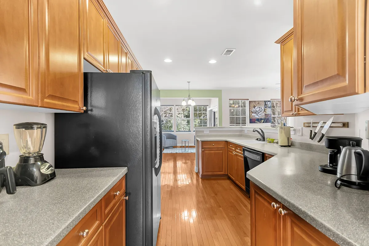 A bright, welcoming kitchen with wooden cabinets, modern appliances, a spacious countertop, and a window offering outdoor views. The space is designed for both cooking and casual entertaining, reflecting the comforts and functionality of a single-family home.