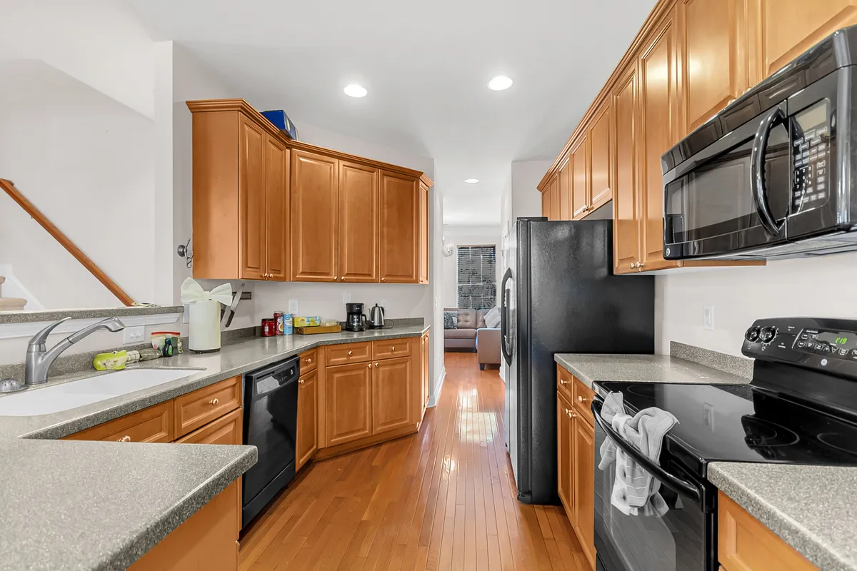 This image captures the kitchen space with prominent kitchen cabinetry, countertops, modern appliances, and warm wooden flooring. The scene feels inviting and ready for both cooking and socializing, with thoughtful organization and ample workspace.