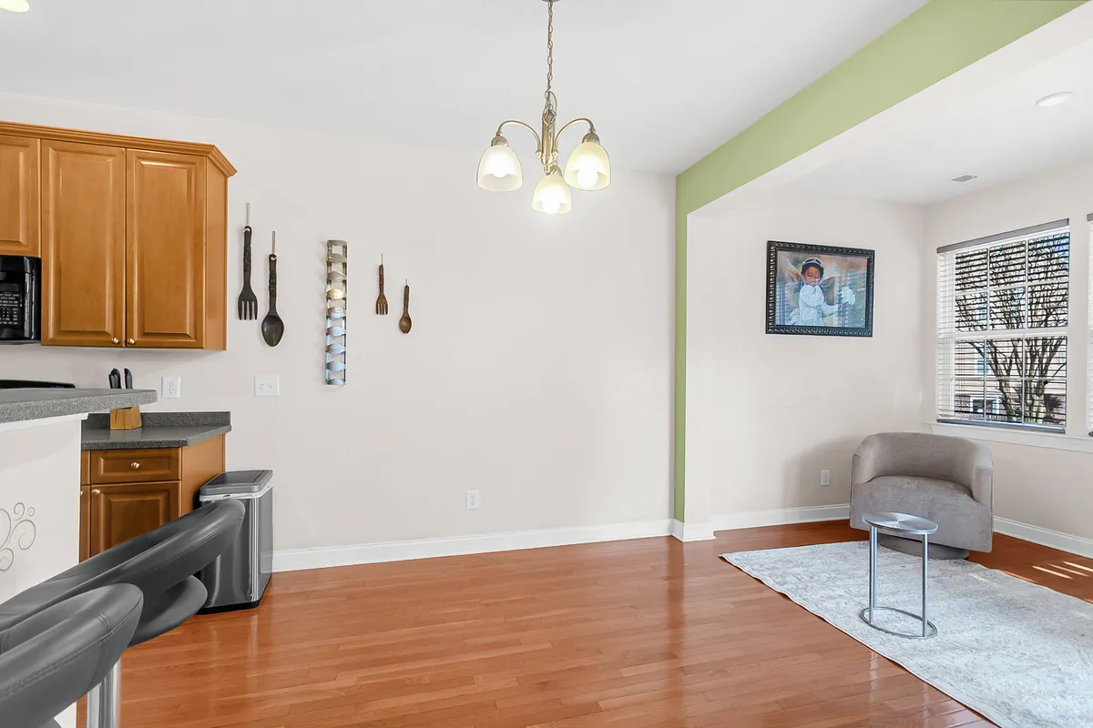 This image presents a combined view of the kitchen cabinetry and adjacent dining area, featuring a cozy seating arrangement and artwork on the wall. The dining table is perfectly positioned for lingering conversations or working remotely.